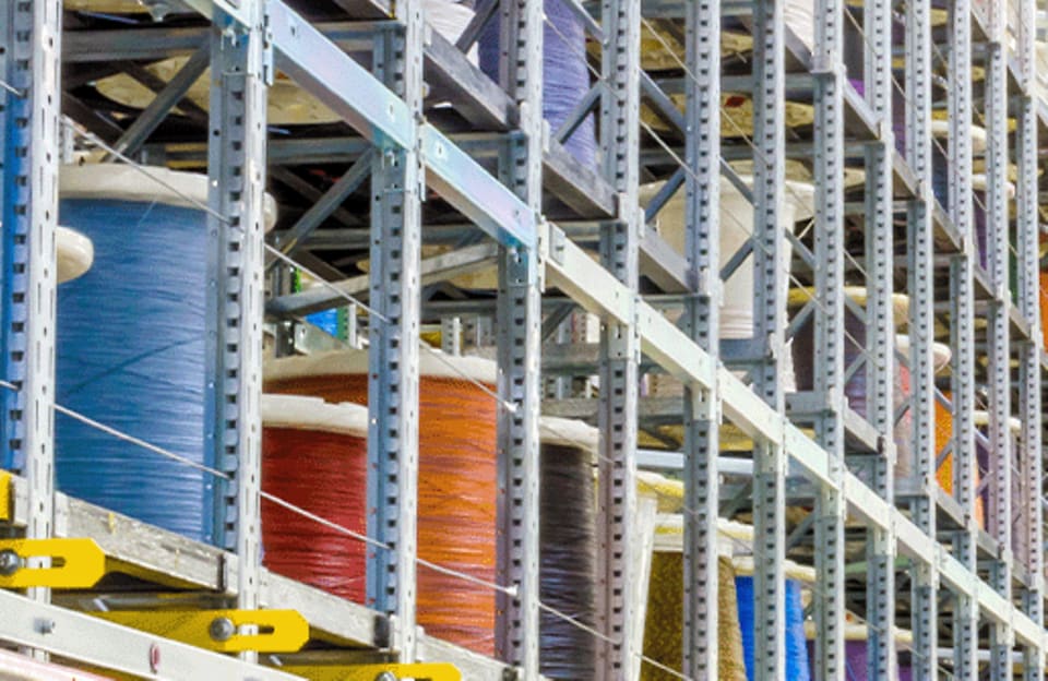 Large inventory of colored feeder wire spools stored on tall racks in a wire center.